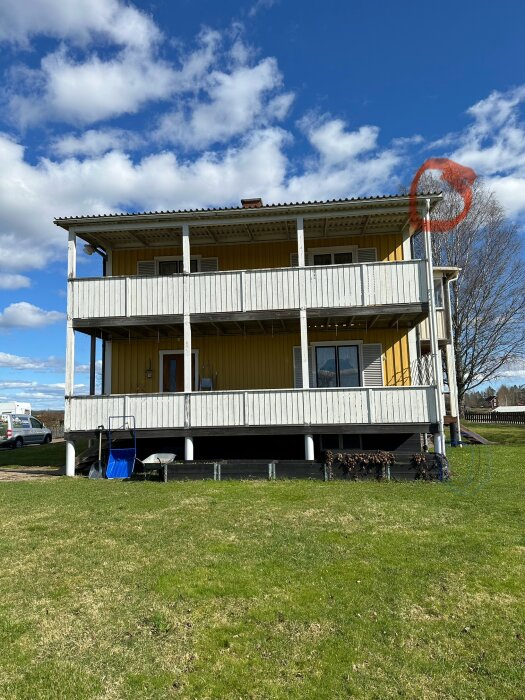 Installation på gult hus med två våningar, gräsmatta, vindskivor markerade med röd ring.
