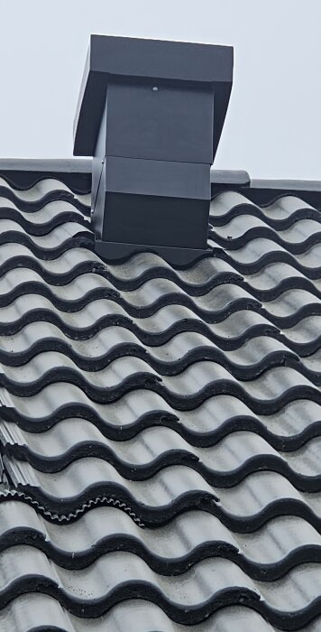 Nytt ventilationshuv monterat på tak med vågformade tegelpannor.
