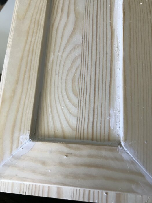 Finsnickeri av trä till bokhylla med nyligen applicerad målarfog vid hörnlist som ger ett "lurvigt" utseende.