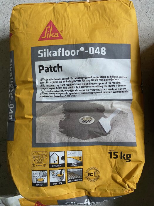 Förpackning av Sika floor 048 patch på ett golv, använd för golvläggning och reparation.