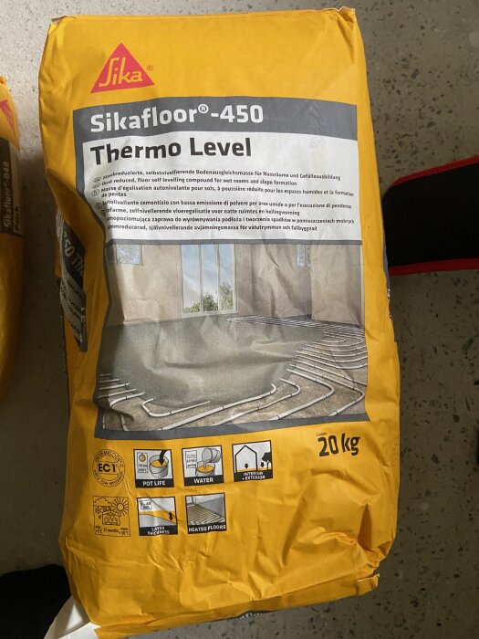Förpackning av Sika floor 450 Thermo Level på ett grovt golv.