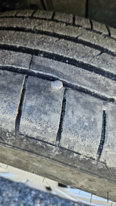 Närbild på en bil däck med en sten fastklämd i mönstret.