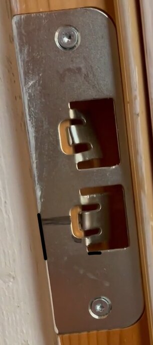 Slitaget på slutblecket till en dörr, med markerade skavmärken som indikerar fallkolvens position.