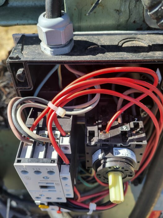 Elektrisk kopplingslåda med flera oanslutna röda och vita sladdar och olika komponenter.