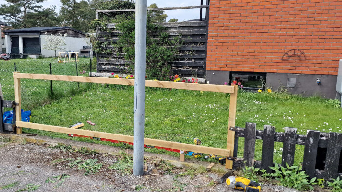 Stomme för staketsektion med tryckimpregnerade stolpar och reglar under konstruktion i en trädgård.
