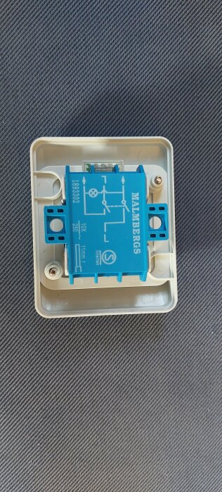 Malmbergs 2-polig strömbrytare med indikeringslampa monterad i en beige plastdosa på en mörkgrå bakgrund.