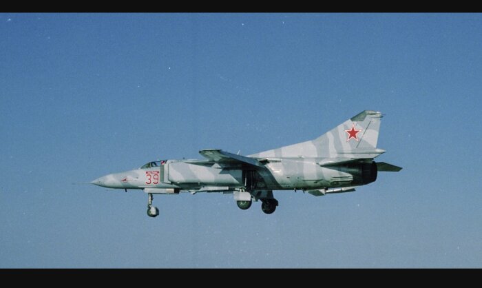 Militärt stridsflygplan med röd stjärna och nummer 39 flyger mot en klarblå himmel.