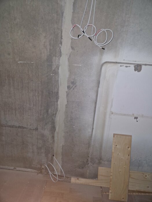 Elektrisk installation i vägg med oskyddade kablar och utmärkt för vägguttag i renoverat kök.
