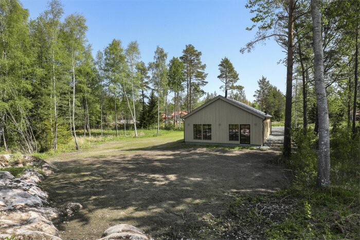 En trädgård i Uppland med öppen yta framför en byggnad, potentiell plats för ett växthus längst norra tomtgränsen.