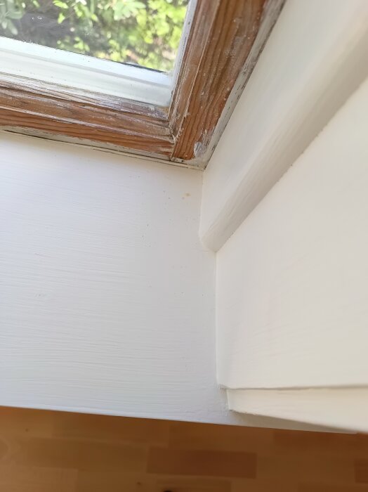 Nymålat fönsterfoder med synliga penseldrag och ojämna ytor, indikerar att slipning mellan strykningarna saknas.