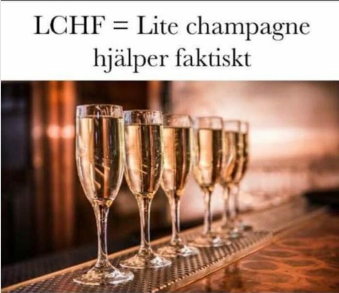 Rad med fyllda champagneglas på bardisk, text "LCHF = Lite champagne hjälper faktiskt" overhead.