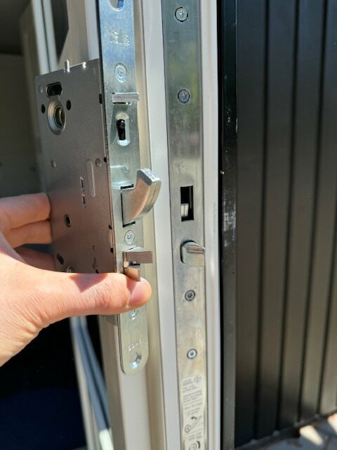 Närhanden visar ett låshus bredvid ett metallskydd på en öppen dörr, potentiell plats för Yale Doorman installation.