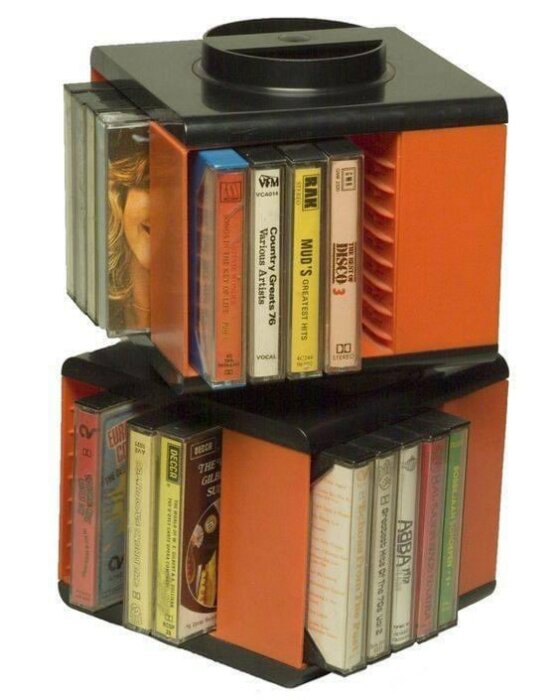 En orange och svart kassettförvaring snurra full med olika musikkassetter.