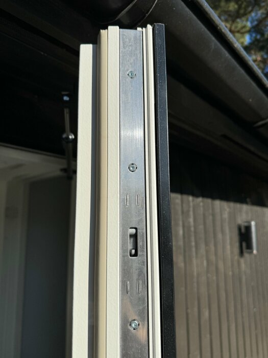 Närbild på detaljer av en dörrkarm och dess tröskel med synliga skruv- och låshål.