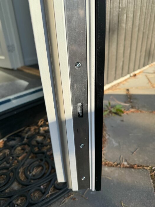 Närbild av öppen dörrkarm som visar justeringsskruvar och tätningar.