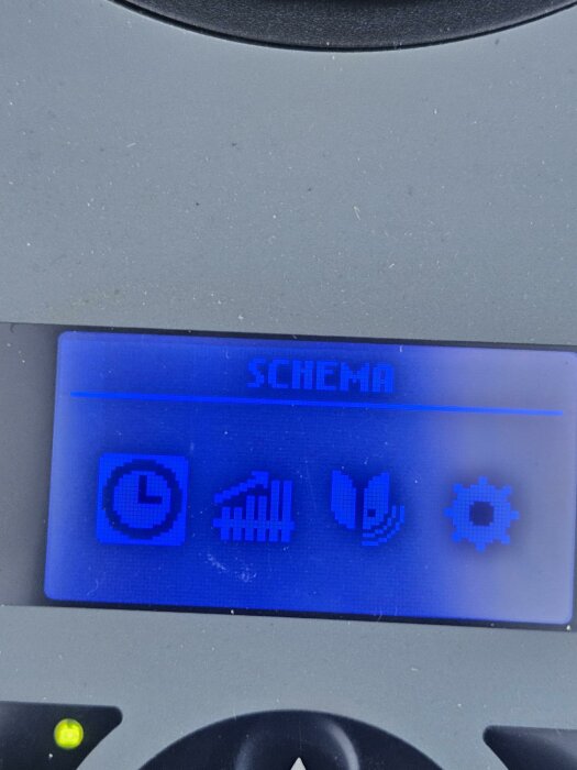 Display på en robotgräsklippare visar schemaläggningsikoner och klocksymbolen i vitt på blå bakgrund.