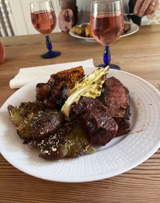 Grillad ryggbiff med smashed potatoes och timjan, grillad svamp, majs, spetskål på en vit tallrik.