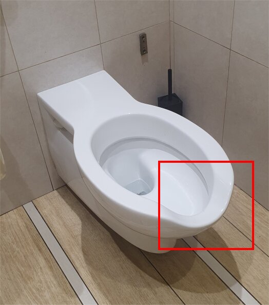 Toalettstol med rundat, integrerat uttag i en herrtoalett, med toaborste vid sidan.