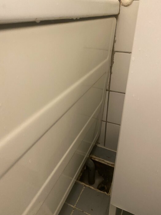 Ett hål i golvet vid toalettstammen i en äldre lägenhet, möjlig avloppsrelaterad orsak.