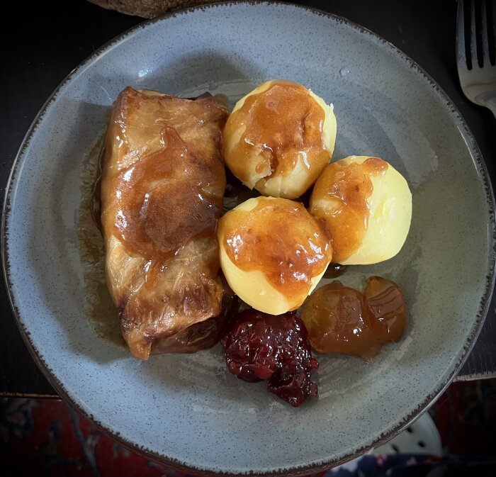 Kåldolme med kokt potatis, lingonsylt och äppelgele på en tallrik.