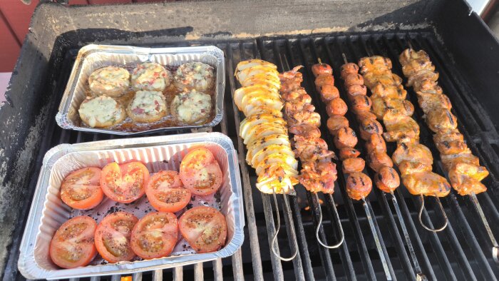 Grillad mat på grill: fyllda champinjoner, kryddade tomater, potatisspiral och köttspett.