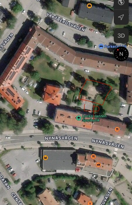 Satellitbild över en innergård med lekplats omringad av byggnader, markerad med röda linjer.