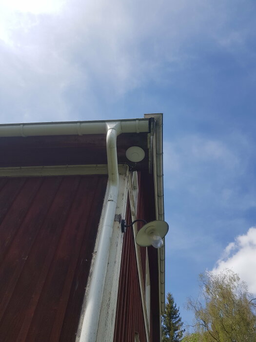 Accesspunkt monterad under takfot på hus med synlig tillfällig kabeldragning längs stuprör.