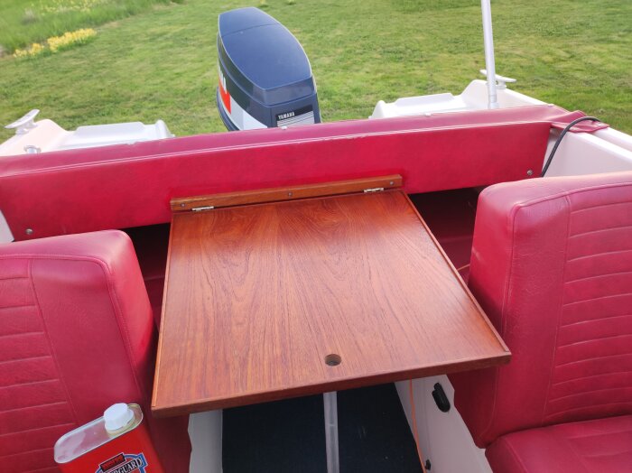 Nyoljad träbord i båt med röda säten och synlig utombordsmotor i bakgrunden.