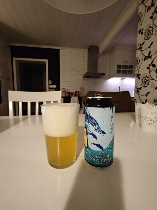 Ölglas halvfullt med skum vid sidan av en burk med märkningen YOLO CITRA på ett köksbord.