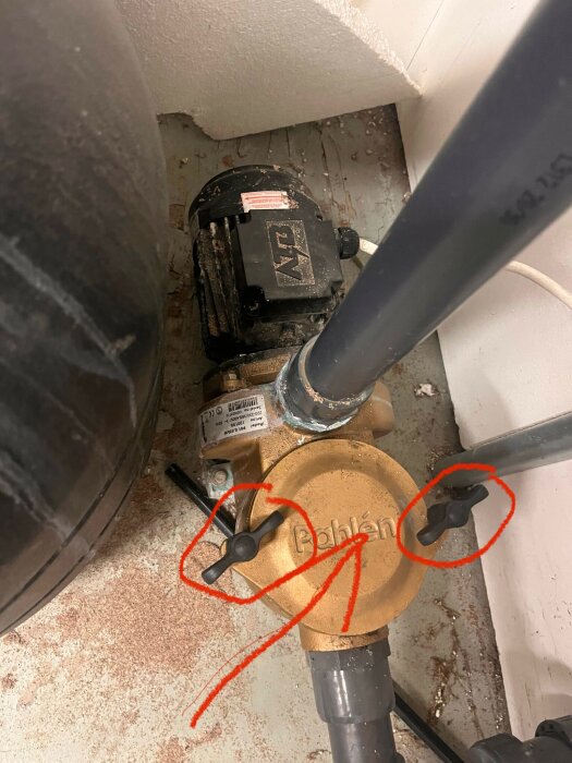 En VVS-installation med en pump och rattar markerade med rött samt en pil som pekar på ett lock.