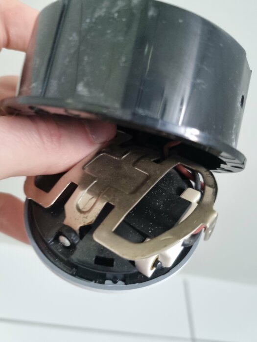 Hand håller en delvis öppnad äldre elektrisk enhet av oklar funktion.