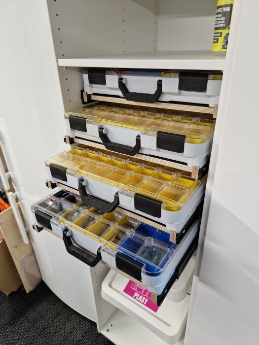 Well-organized storage system in a garage with clear multi-compartment boxes on shelves for efficient space optimization.