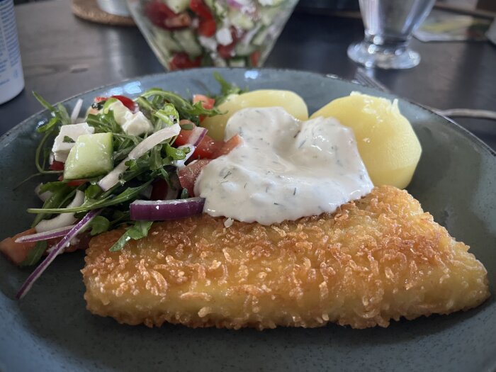 Panerad torsk med kokt potatis och dill-citronsås, serverad med en fetaostsallad.