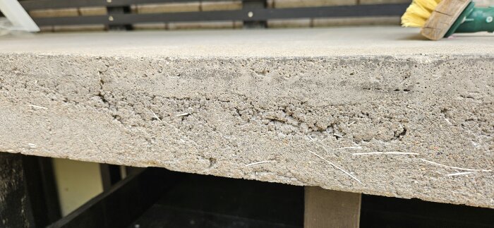 En skadad betongbänkskiva med gropar och håligheter längs kanten.