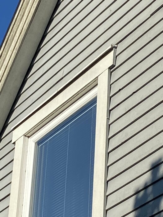 Fönster utan överplåt på en fasad med liggande fjällpanel och synlig vindskiva.