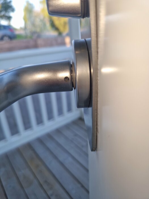 Närbild på dörrhandtag utan synlig skruv eller monteringsmekanism fastsatt på en vit dörr.