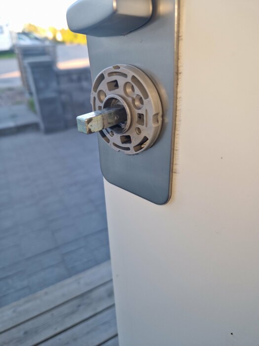 Närbild på en dörr med låscylinder och utstickande nyckel, med en komplex metallbricka bakom.