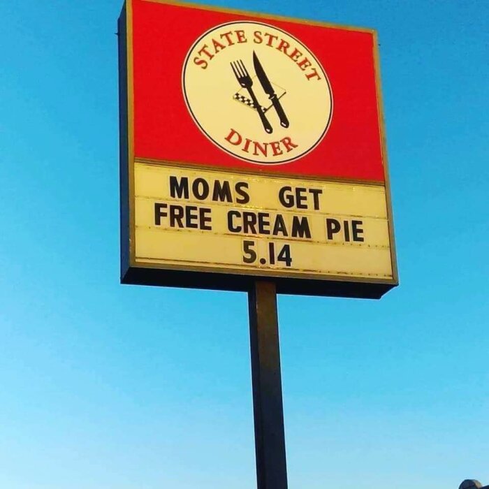 Skylt med texten "Moms get free cream pie 5.14" på State Street Diner mot blå himmel.