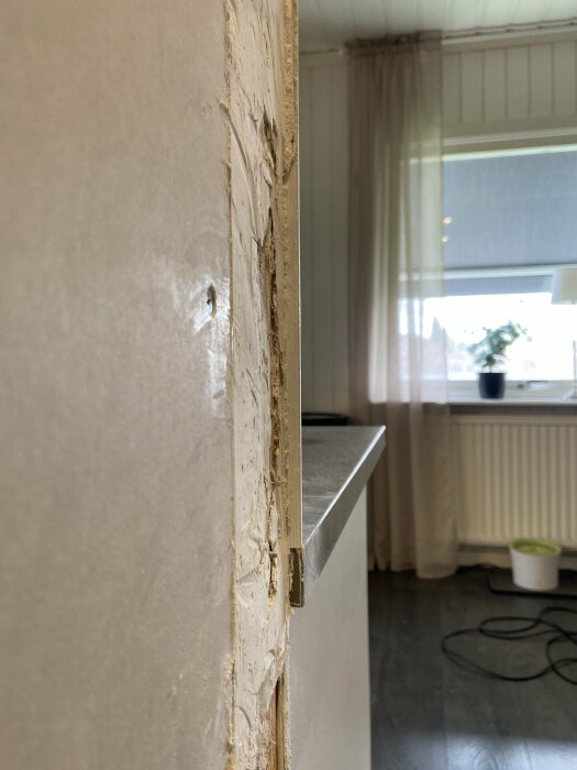 Överblick av en ojämn väggövergång med synlig spackel och råa kanter vid ett kök efter borttagning av garderober.