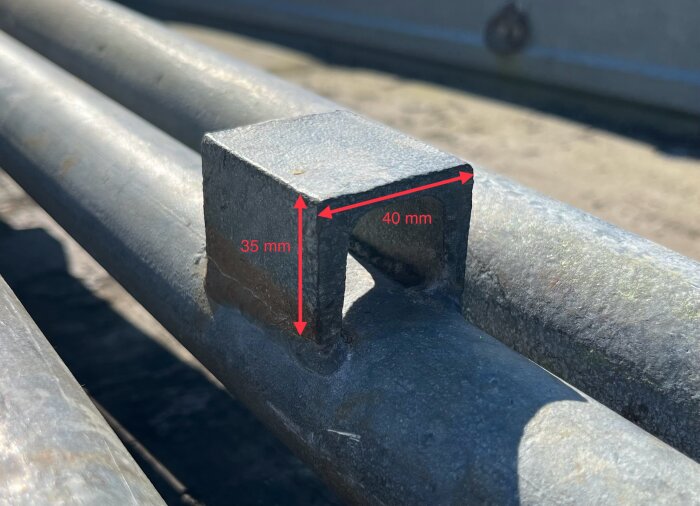 Närbild på en byggställningskoppling med dimensionerna 35 mm och 40 mm markerade på metallstycket.