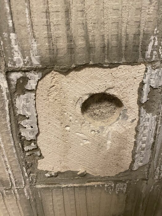 Bild på en vägg med gammal, porös puts och spår efter kakelfix, visar renoveringsbehov i badrum.