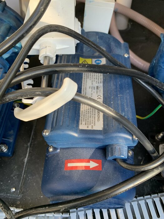 Blå motorpump med elektriska kablar och ett varningsmärke, indikerad som inaktiv.
