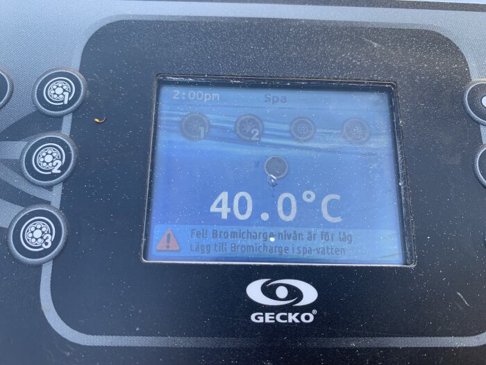 Spabadets digitala display visar en vattentemperatur på 40.0°C och en varningsikon om låg bromnivå.