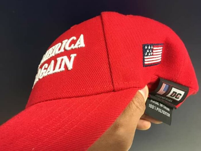 Röd keps med texten "Make America Great Again" och en amerikansk flagga.