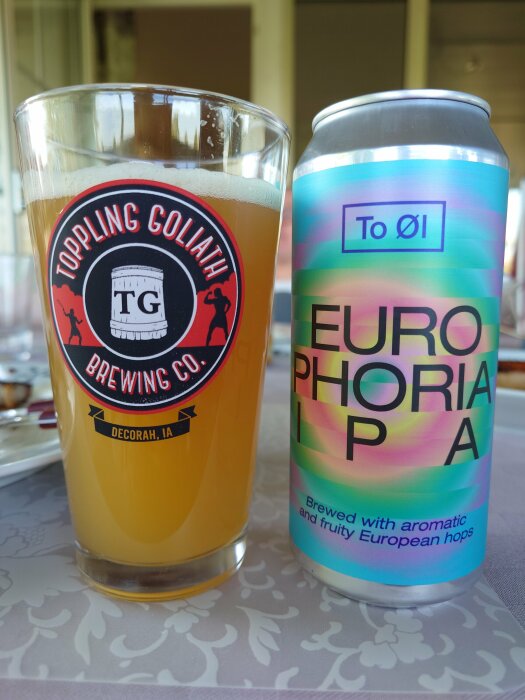 Ett glas med öl bredvid en ToØl Europhoria IPA ölburk på ett bord.