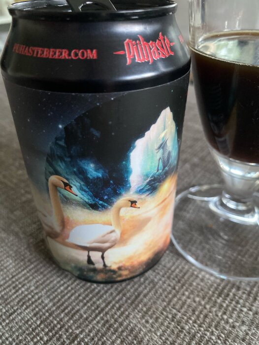 En Stout-ölburk från Pühaste med svanmotiv bredvid ett glas med mörk öl.