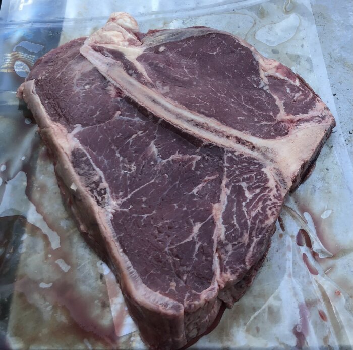 Enorm T-bonesteak på över 900g, större än en mattallrik, på plastförpackning.