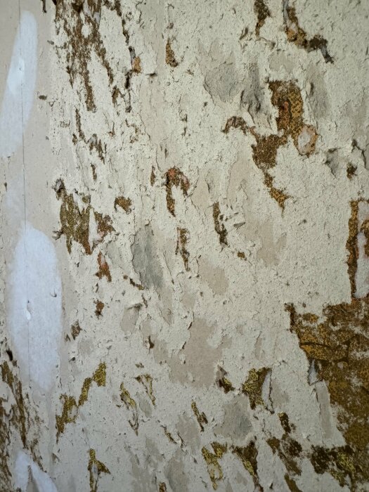 Ojämn vägg med rester av gammal tapet och klister, potentiellt för renoveringstapet.