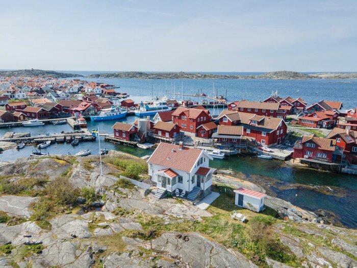 Flygfoto över Käringön med röda och vita hus, båtar och klippor vid Bohusläns kust.