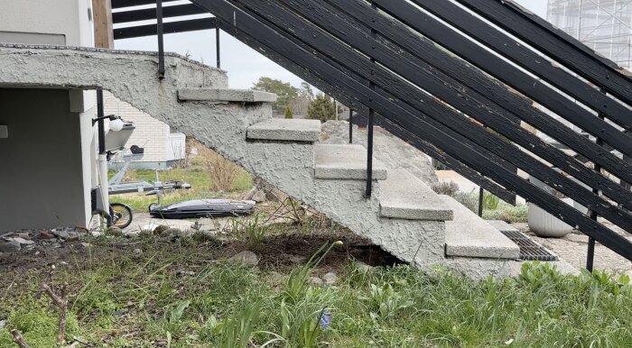 Nedsliten betongtrappa med skadad yta och bortfallande bitar vid en villa, behöver renovering.